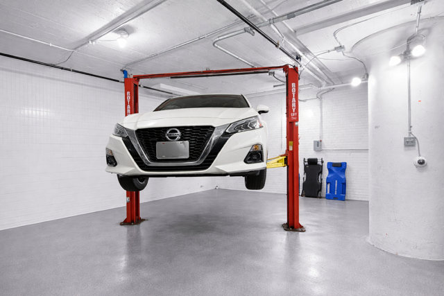 Vehicle raised on lift, front face view showing undercarriage clearance
