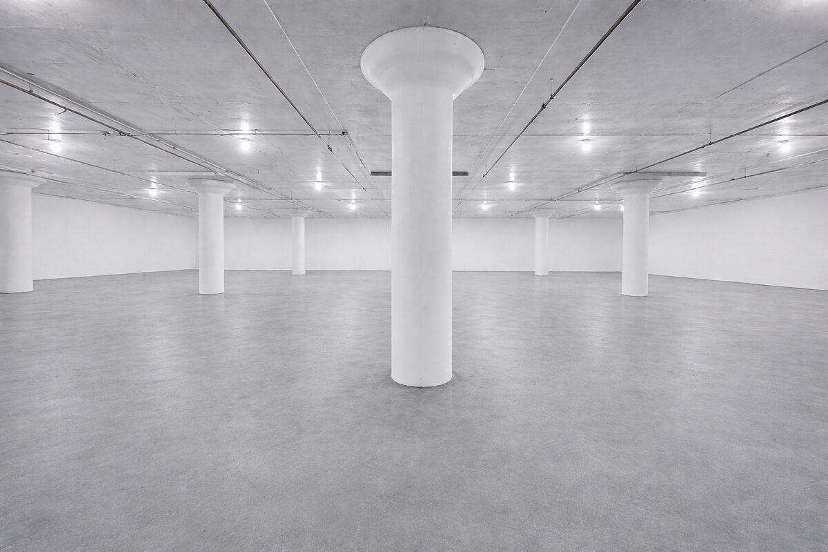 Wide view of indoor vehicle storage area showing full column row and ceiling lights
